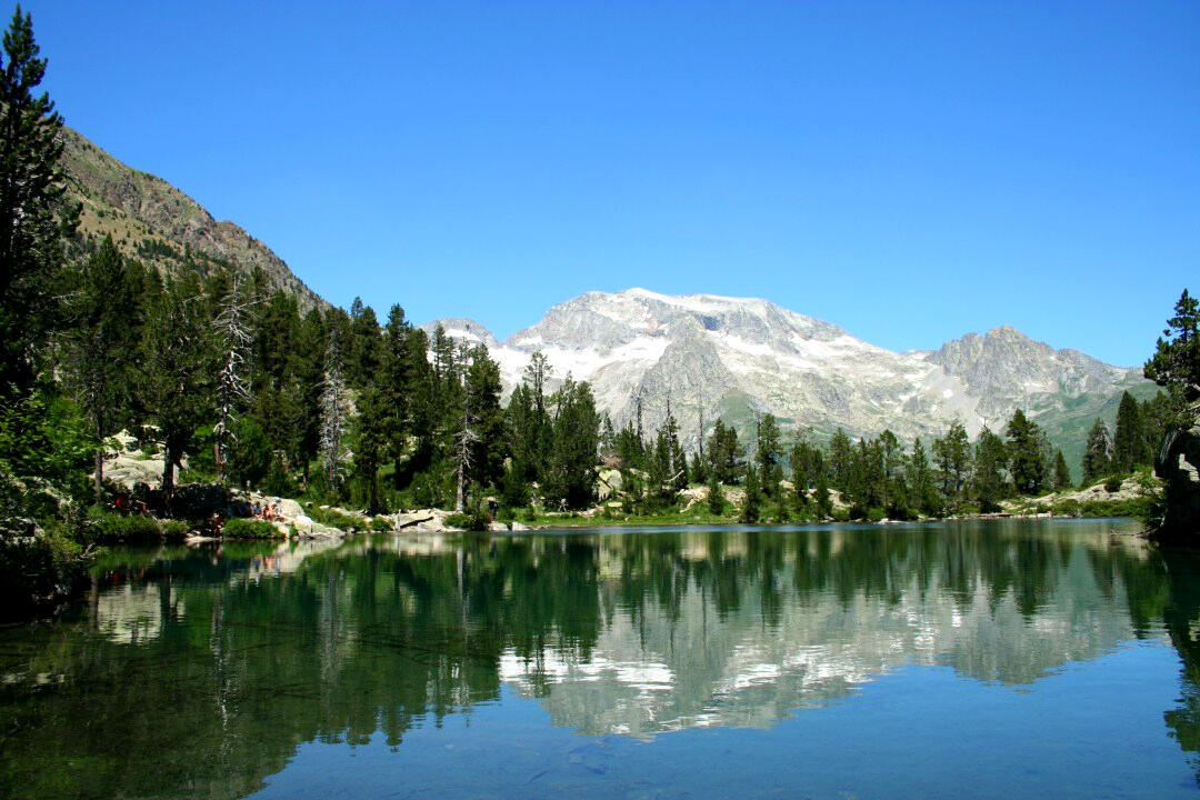 Lago cristalino rodeado de pinos y montañas en Aragón, localización perfecta para rodajes naturales.